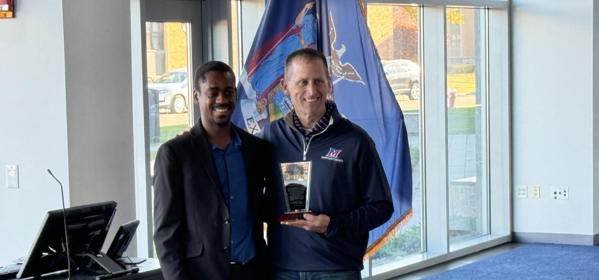 Two men taking a photo with the National Society of Black Engineers award